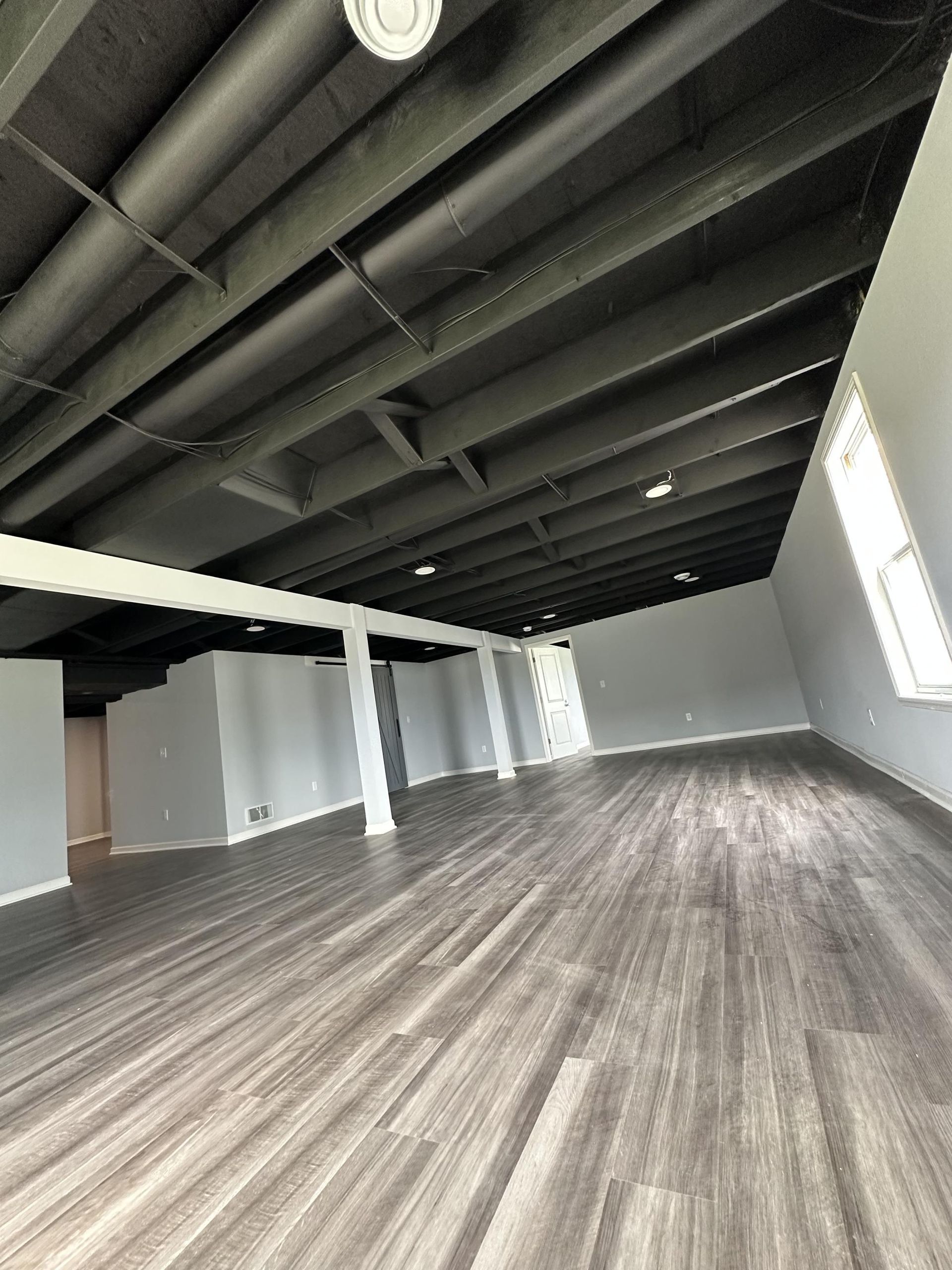 A large empty room with a wooden floor and a black ceiling.