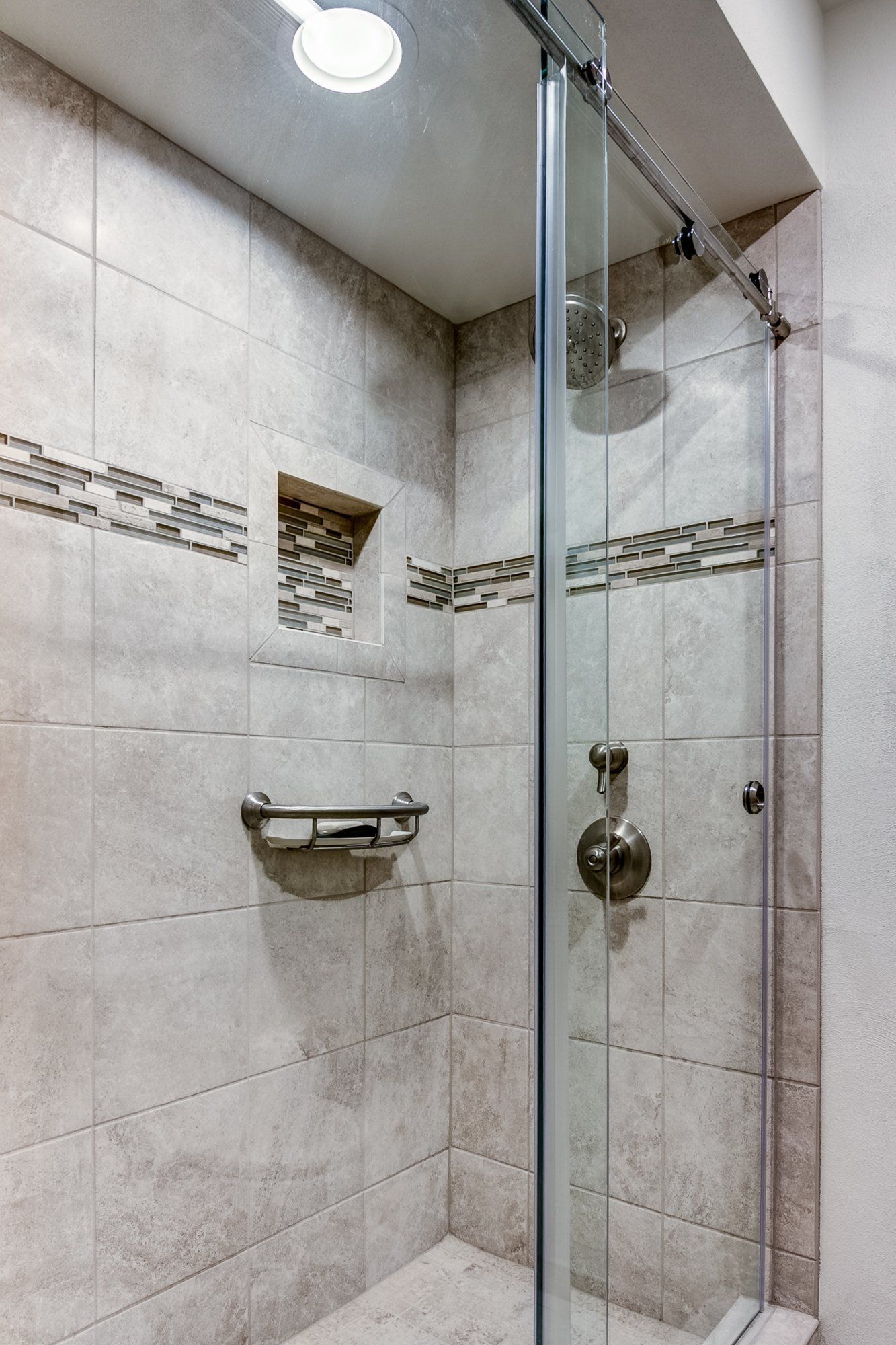 A bathroom with a walk in shower with a sliding glass door.