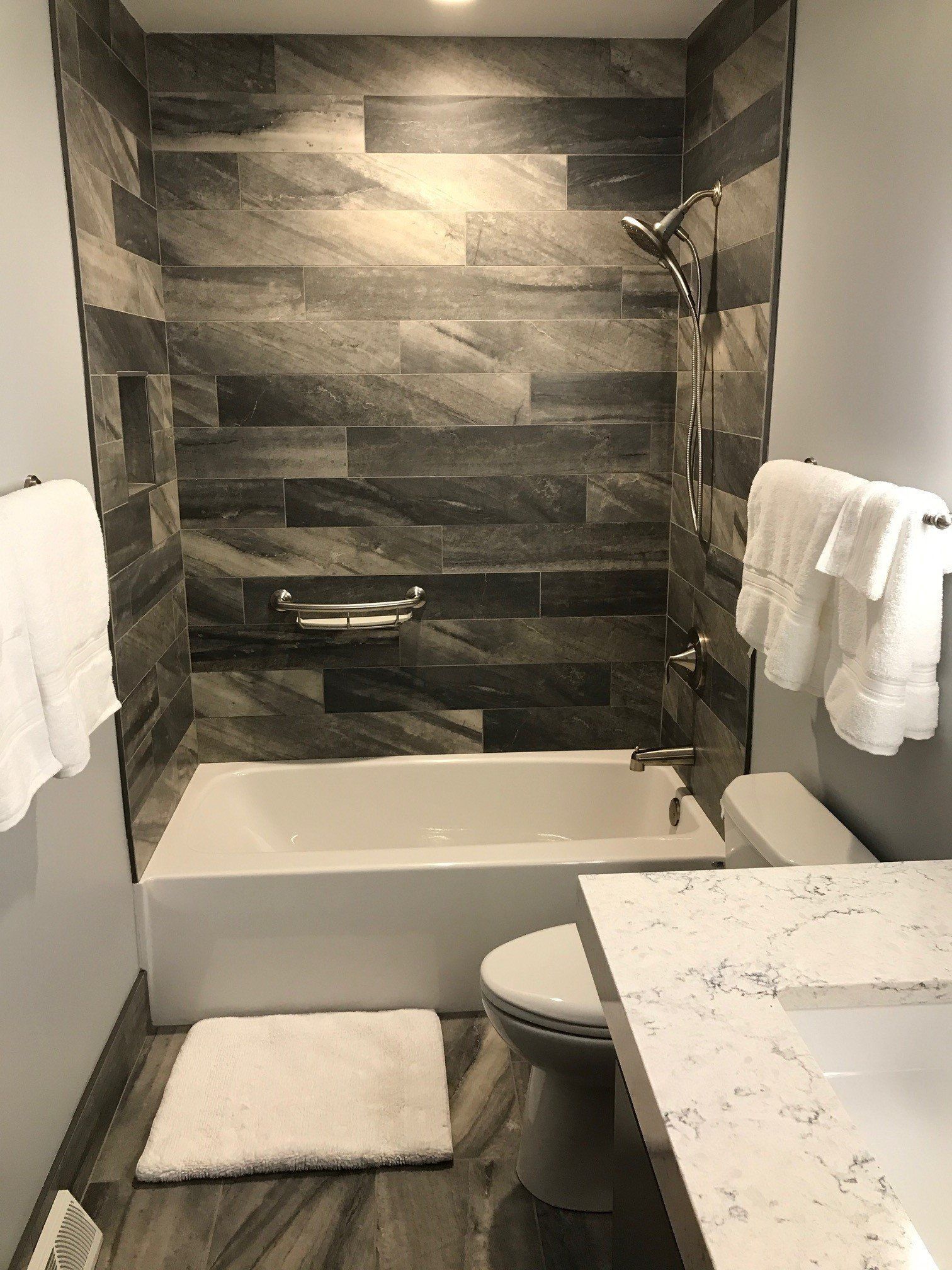 A bathroom with a tub , toilet , sink and shower.