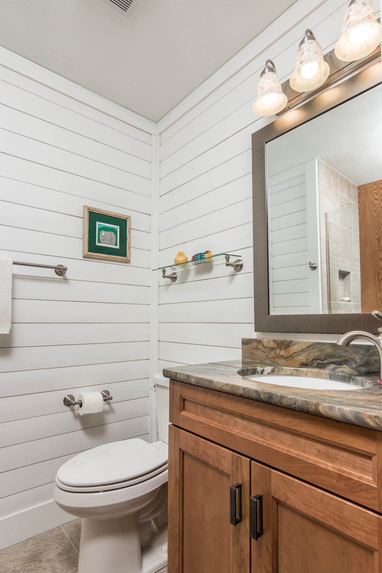 A bathroom with a toilet , sink and mirror.