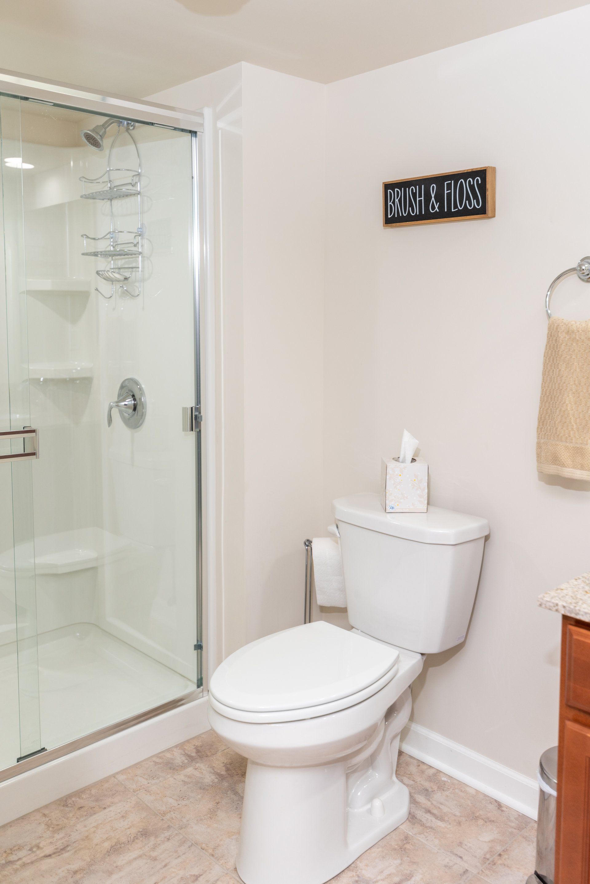A bathroom with a toilet and a shower with a sign above the toilet that says ' please wipe '