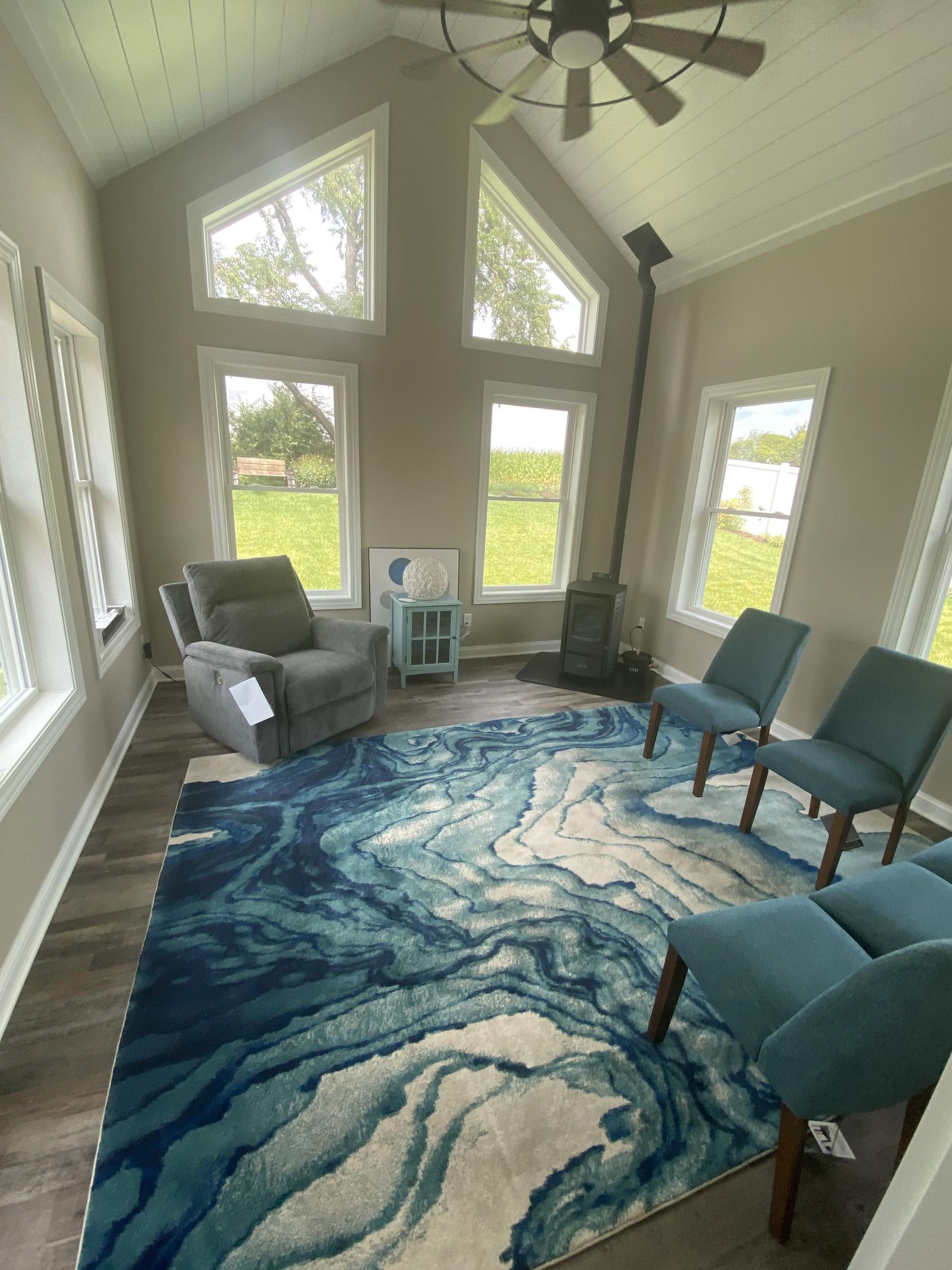 A living room with a rug , chairs , and a ceiling fan.