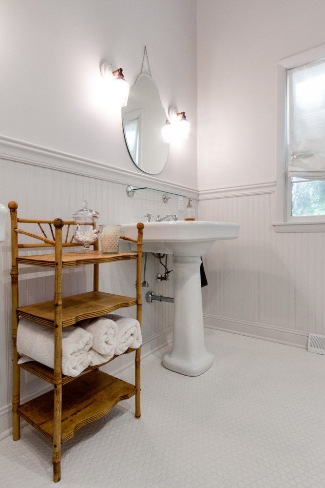 A bathroom with a sink and a wooden shelf with towels on it.