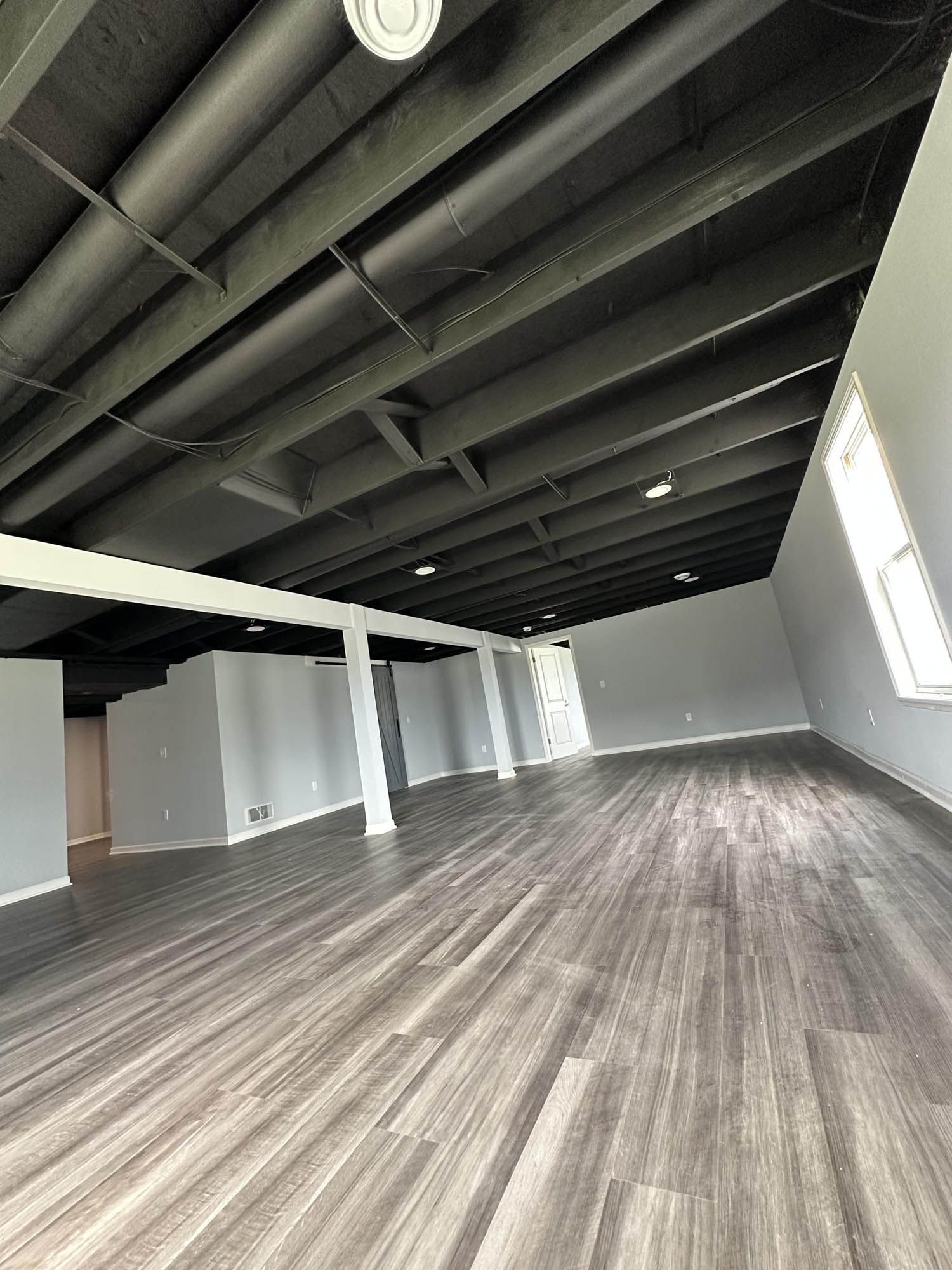 A large empty room with wooden floors and a black ceiling.