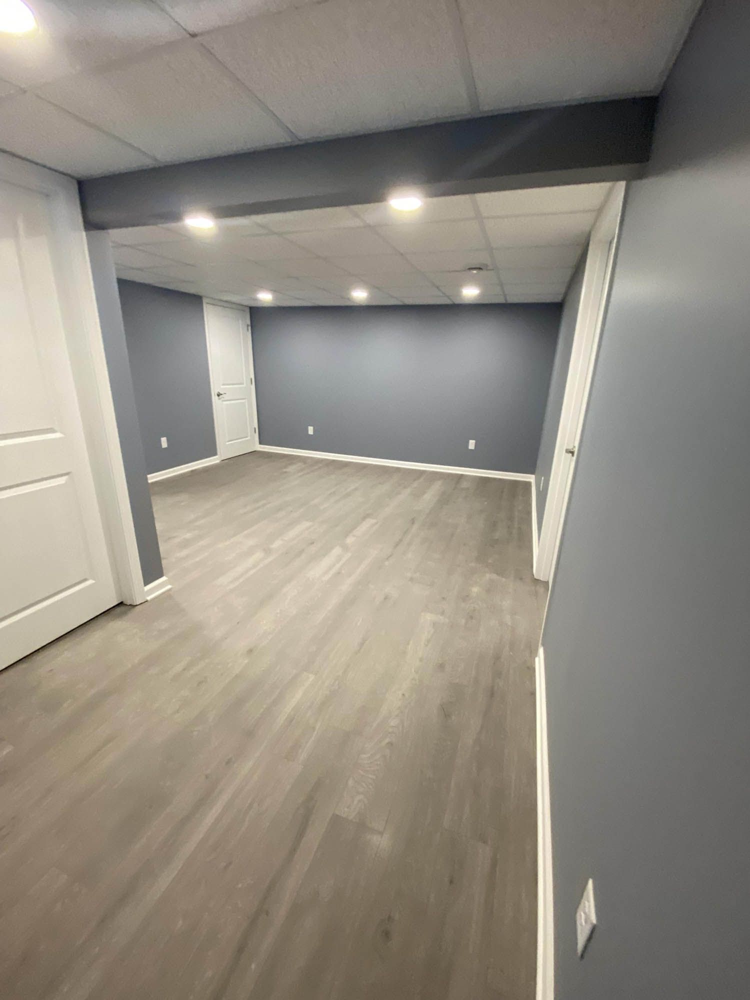 An empty basement with hardwood floors and gray walls.