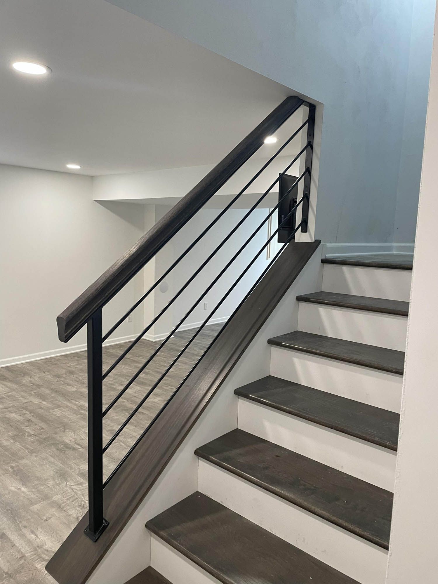 A set of stairs with a black railing in an empty room.