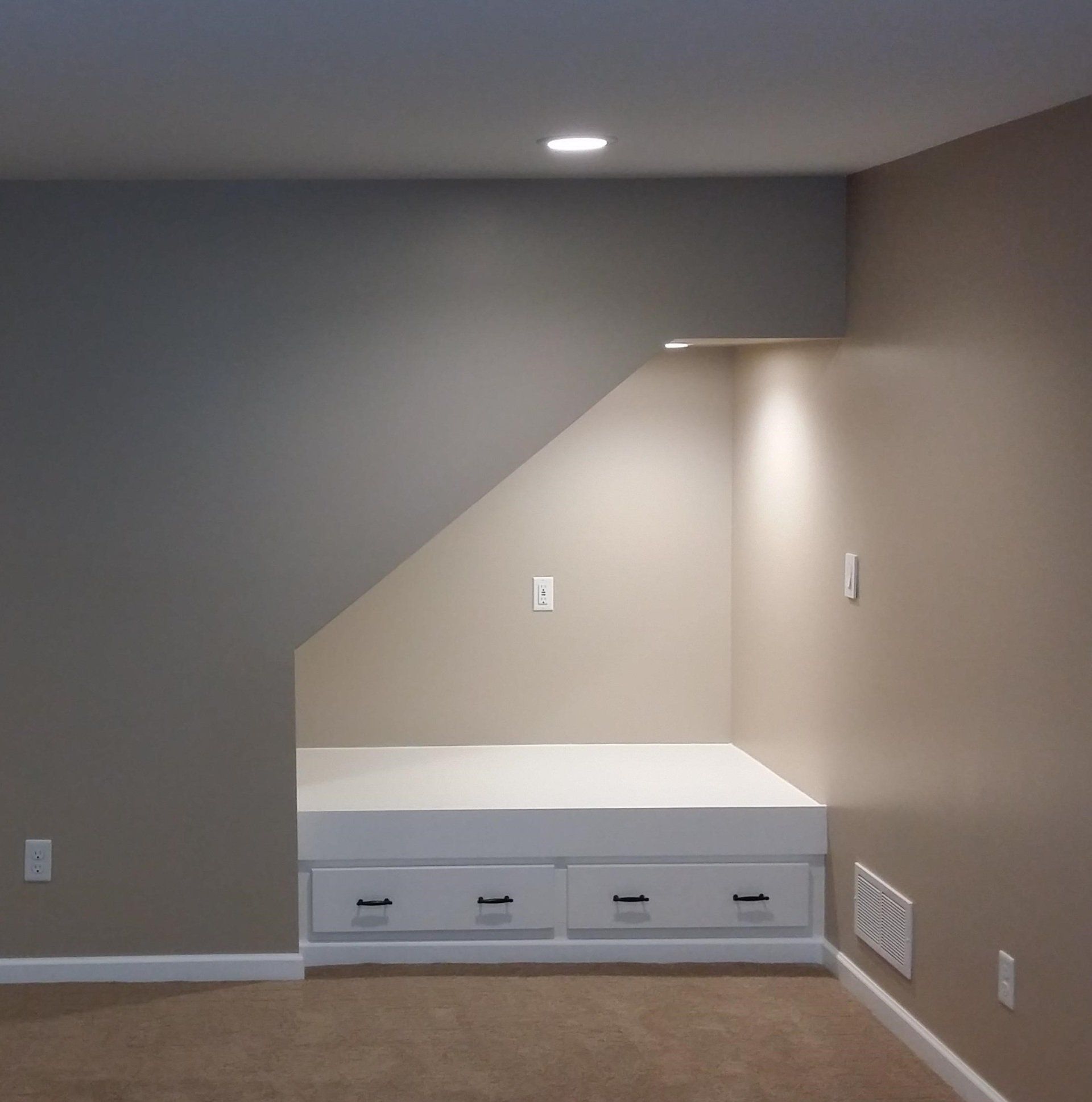 An empty room with a bed under the stairs