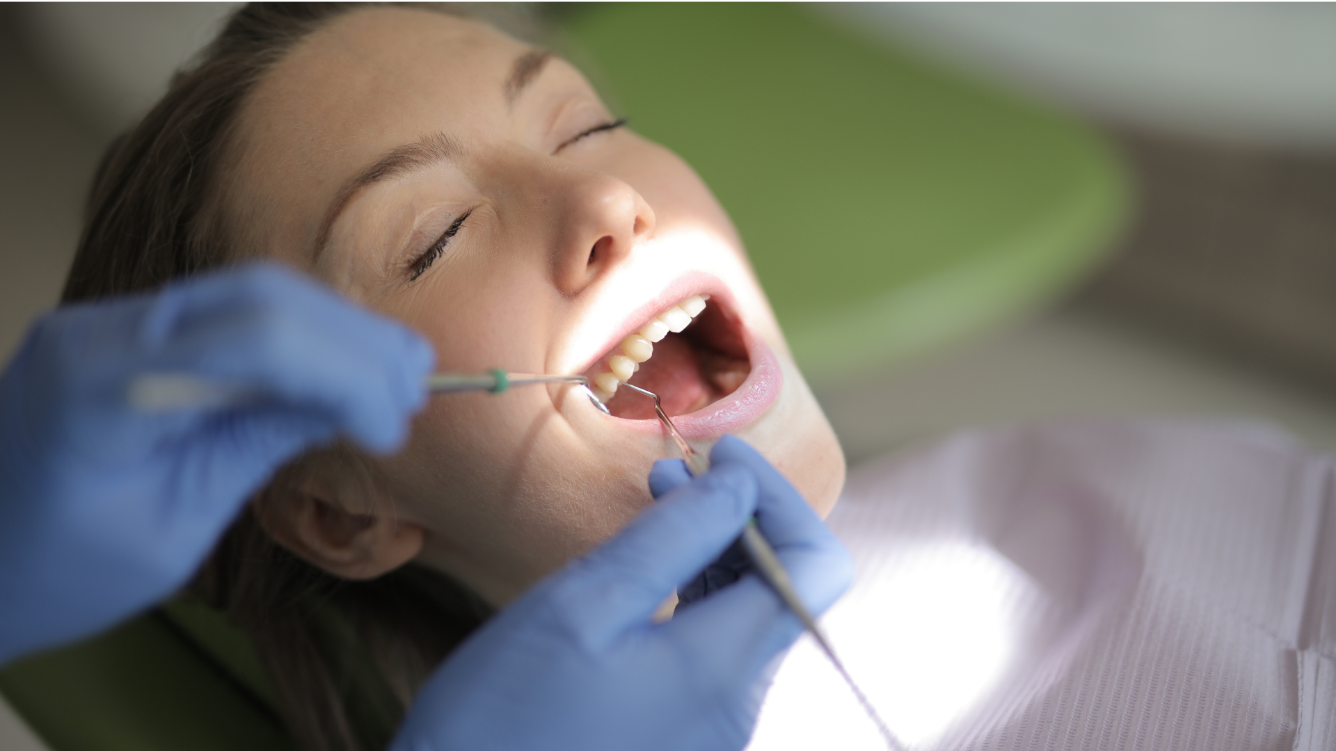 A woman is having her teeth examined by a dentist.