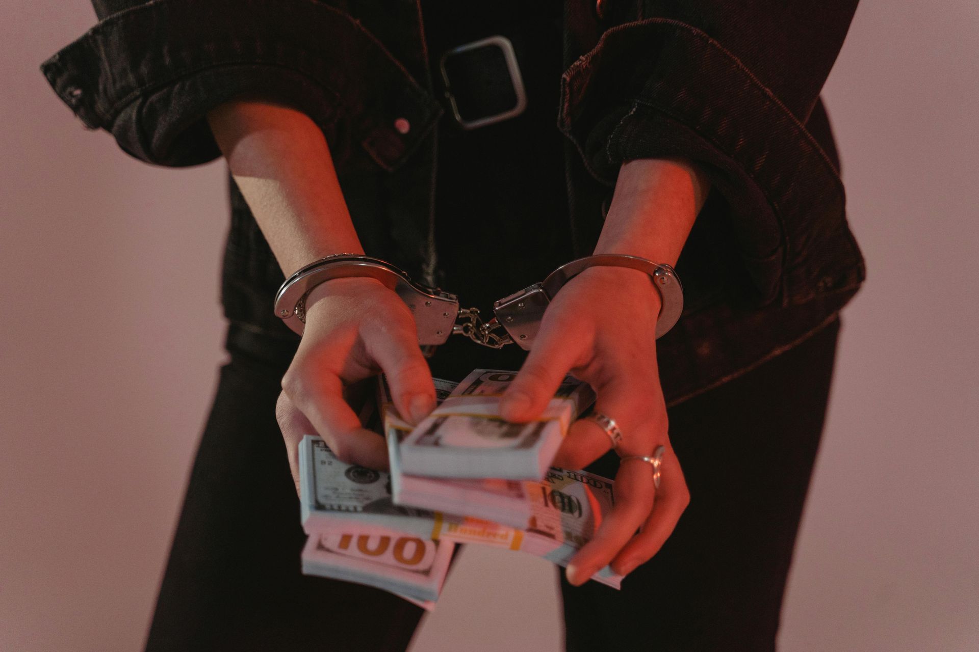 a woman handcuffed with a stack of money in her hands