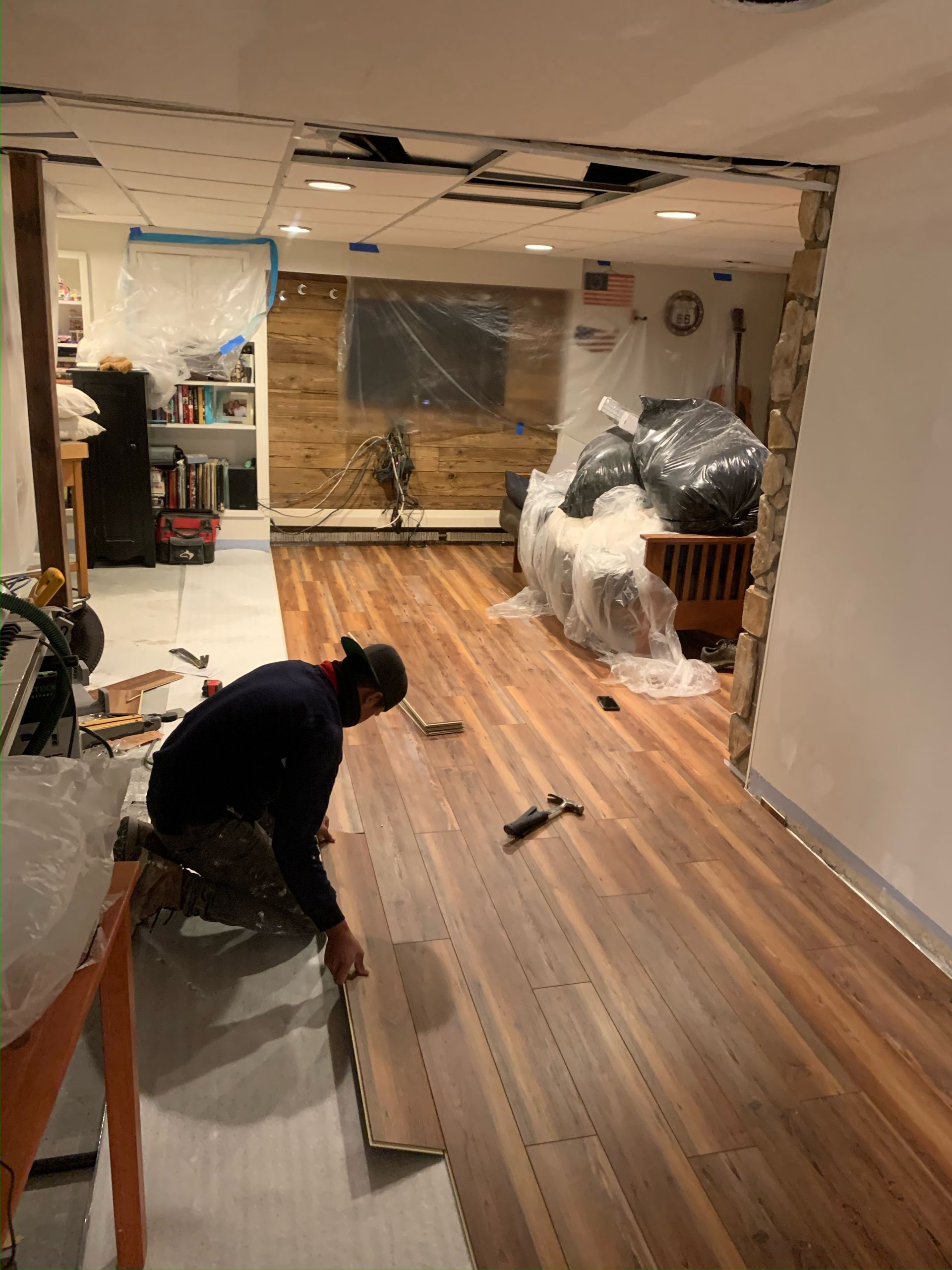 A man is working on a wooden floor in a room.