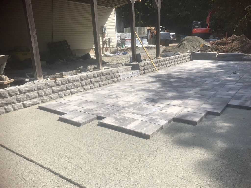 A patio is being built in the backyard of a house.