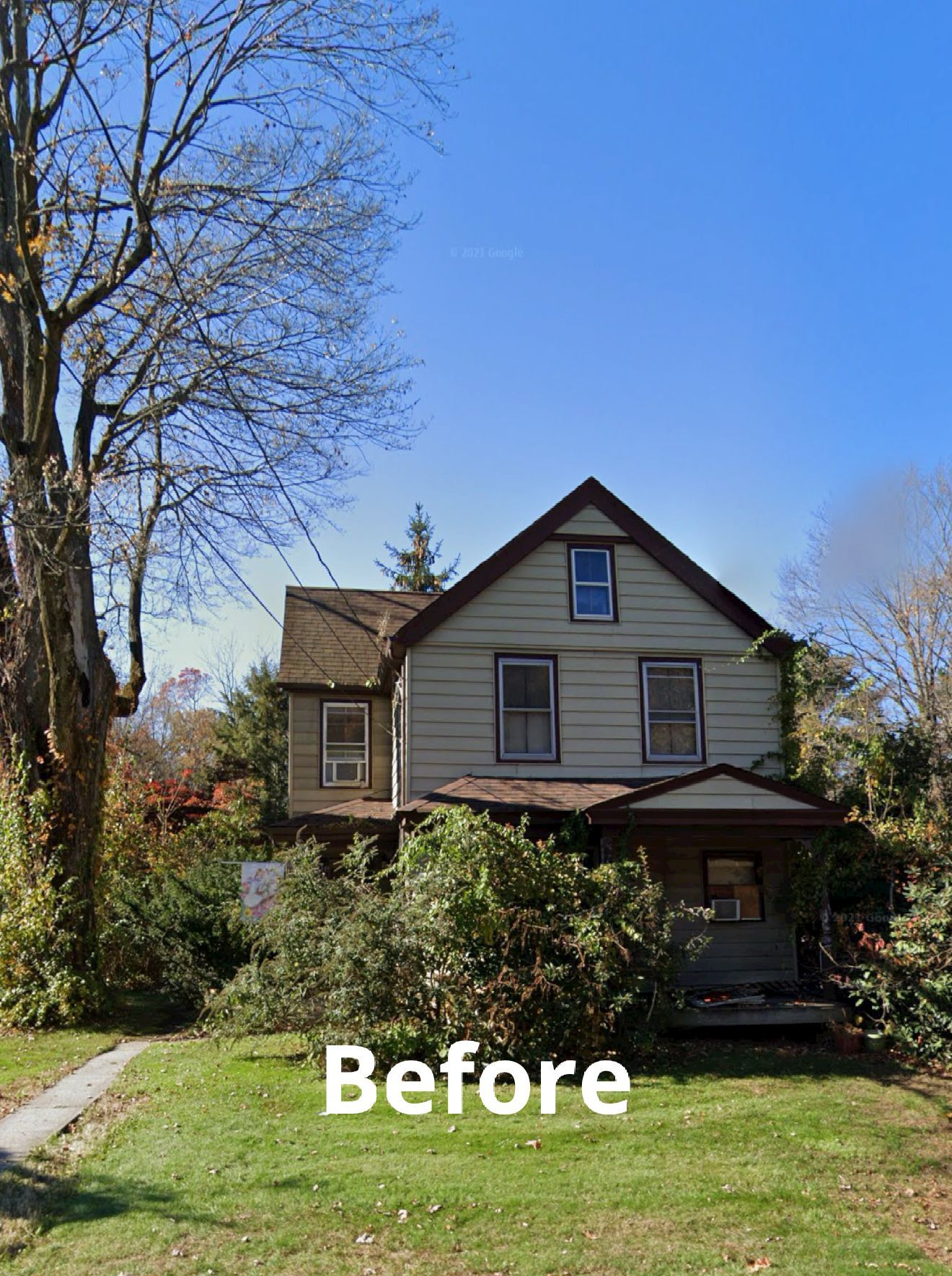 Before view of a gray two-story house with a front porch and overgrown yard under a clear blue sky