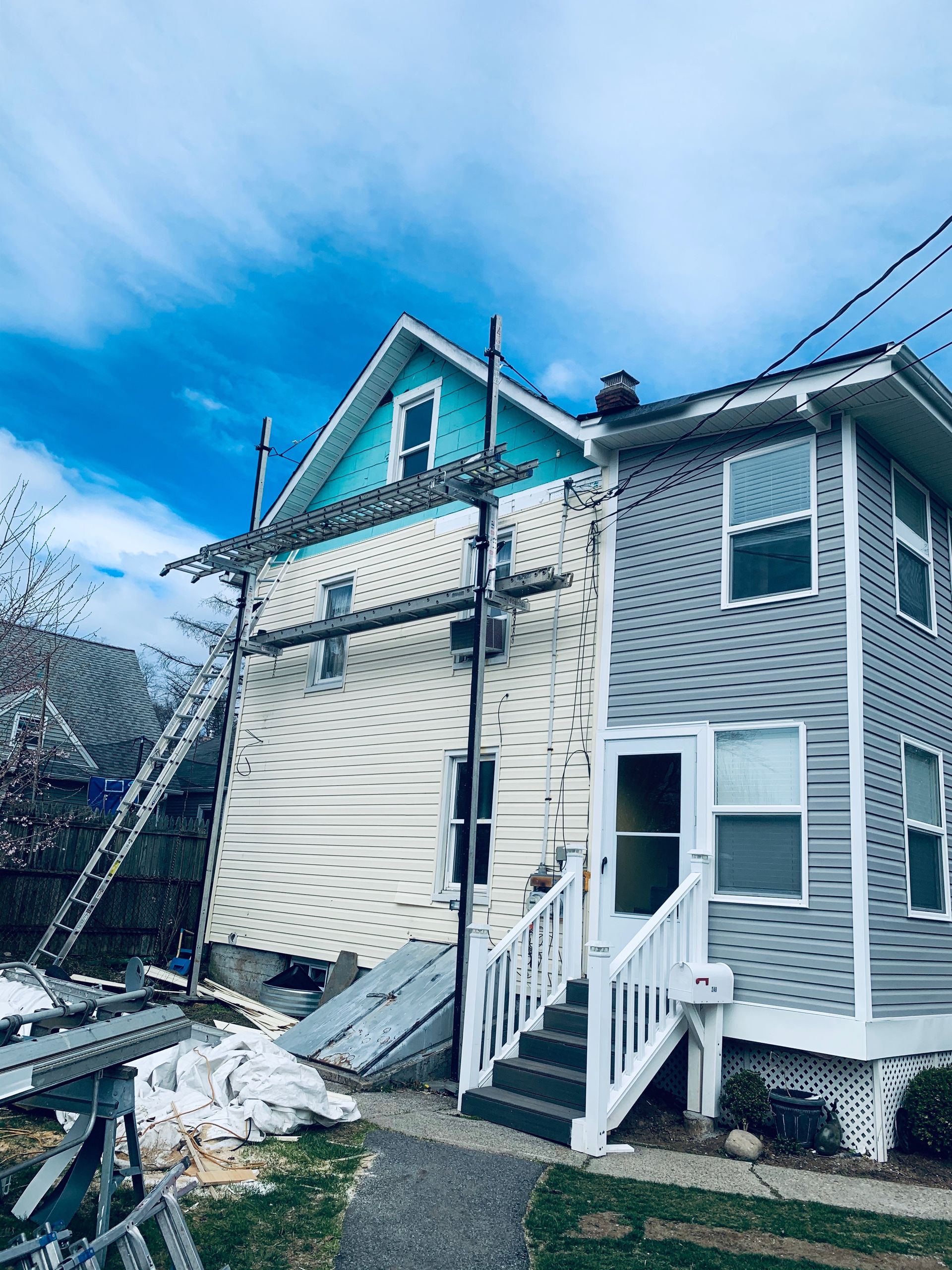 A house with a blue roof is being painted.