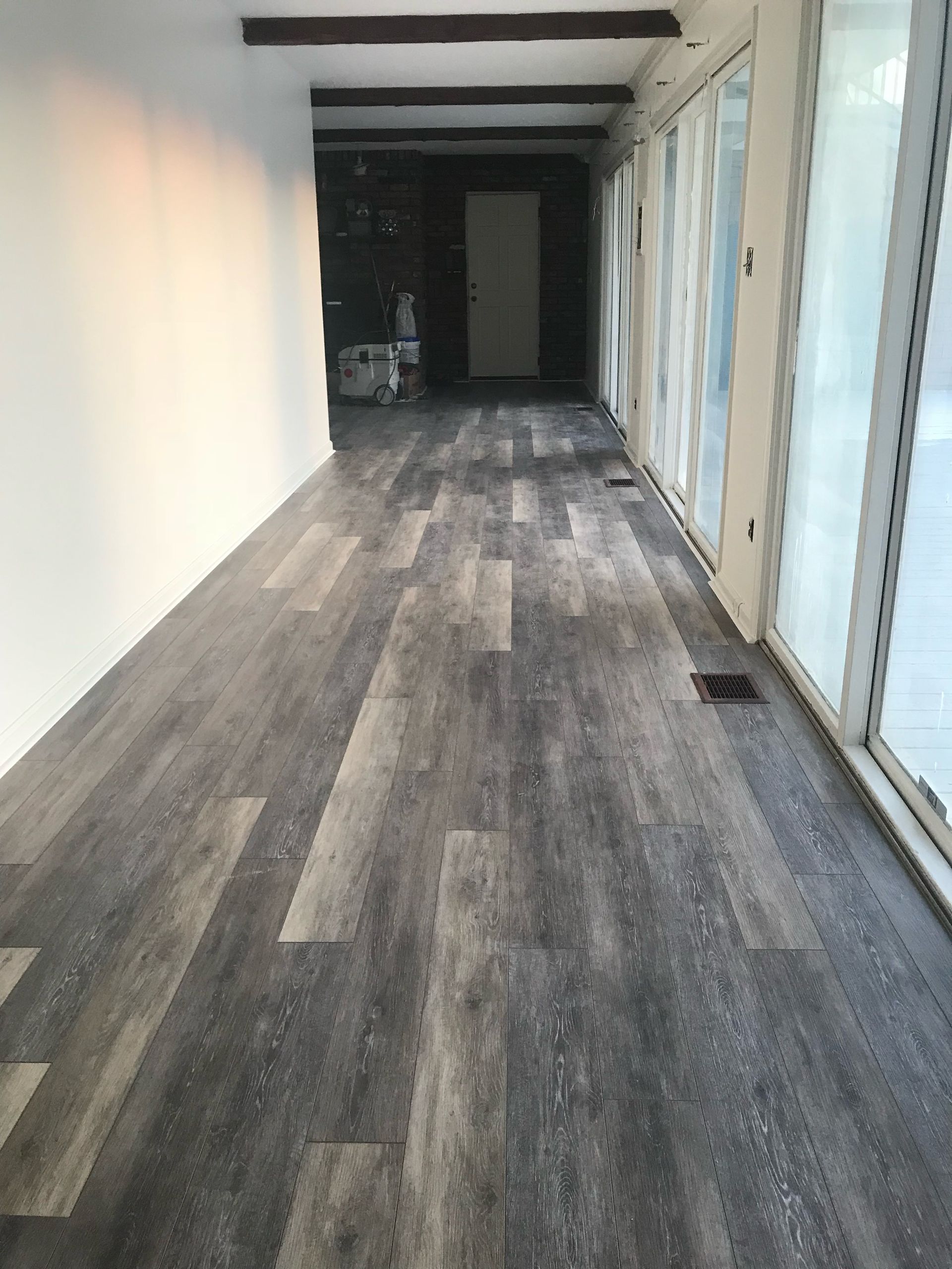 A long hallway with hardwood floors and lots of windows.