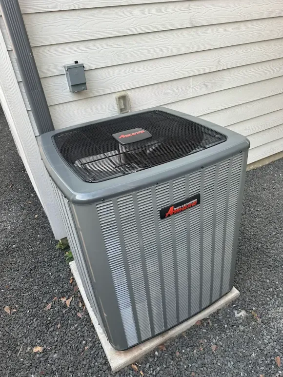 Air conditioning unit outside a building, surrounded by greenery.