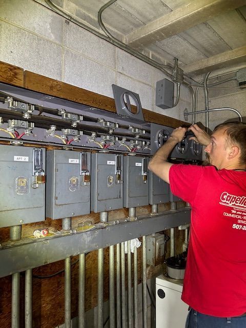 Technician in red shirt working on electrical panels in a utility room