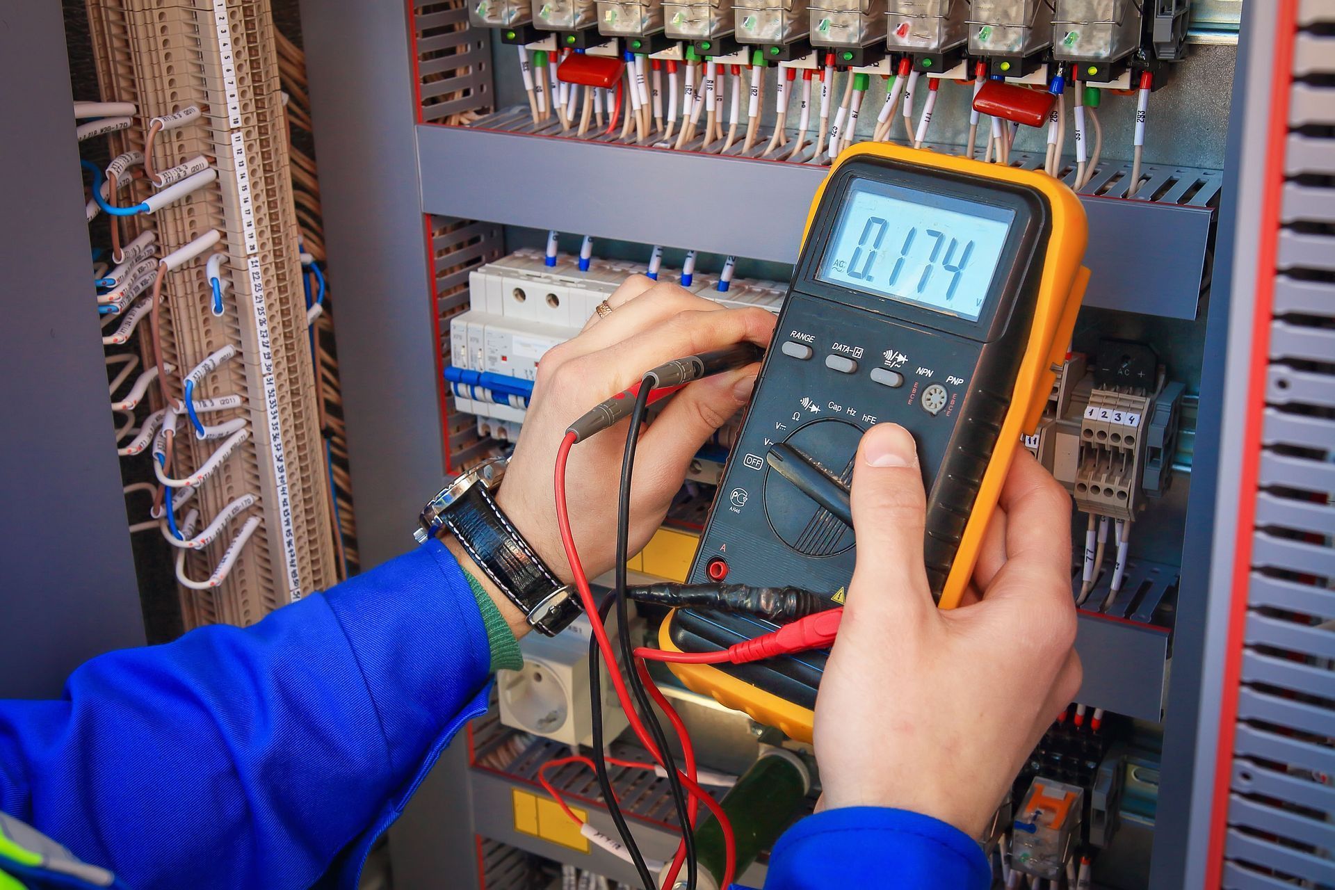 Technician testing electrical panel with a multimeter in a server room