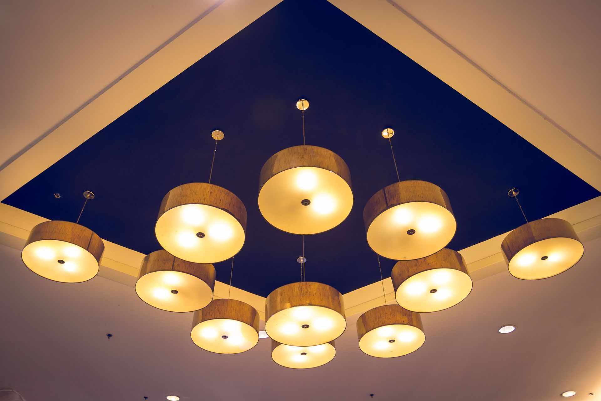 Cluster of warm pendant lights on a dark blue ceiling panel in a modern room