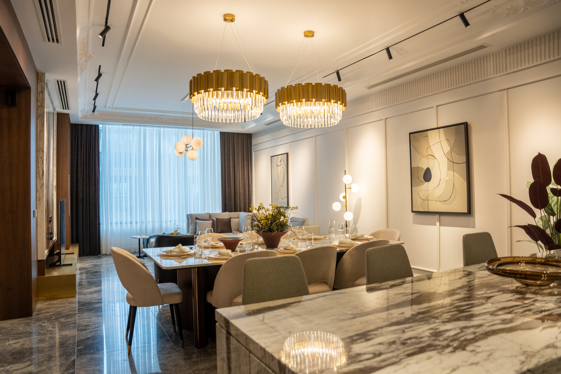 Modern dining room with crystal chandeliers, marble table, upholstered chairs, and large window curtains