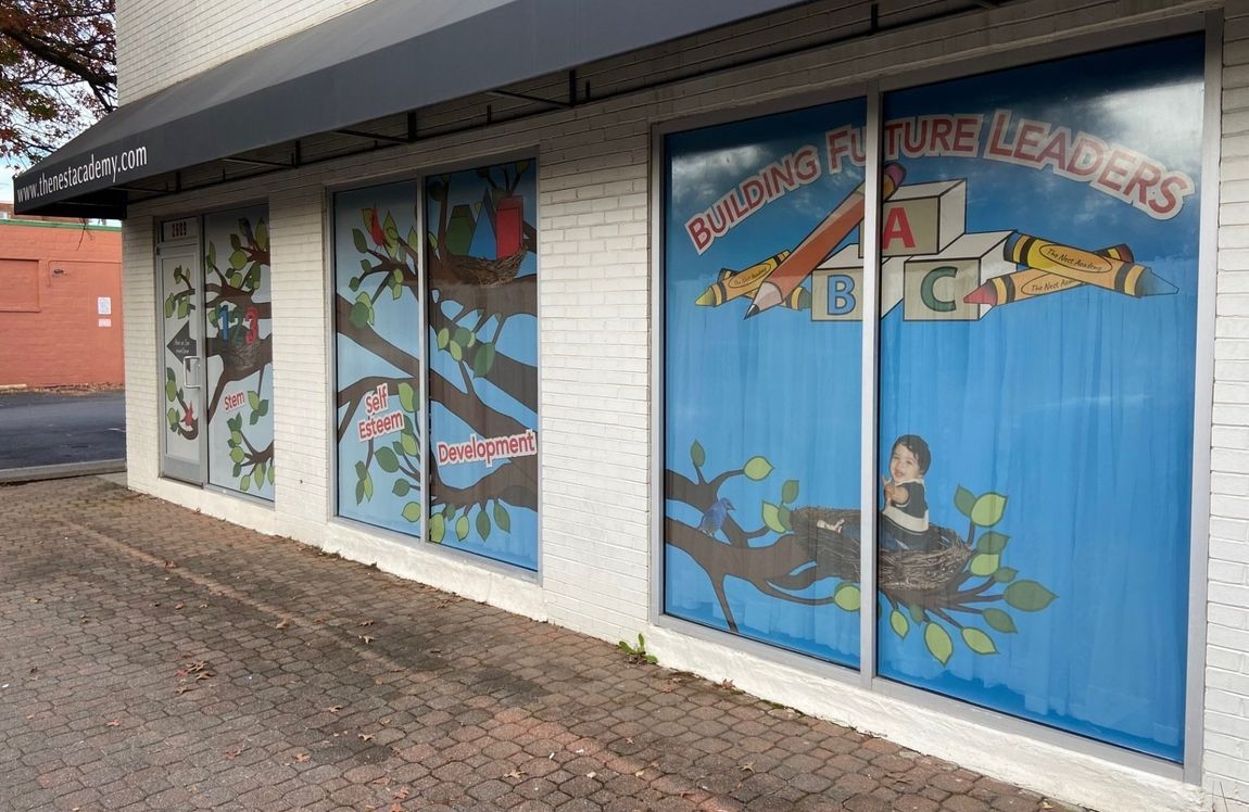 Storefront windows with colorful cartoon bird murals and blue “Birds” signage on a white brick building