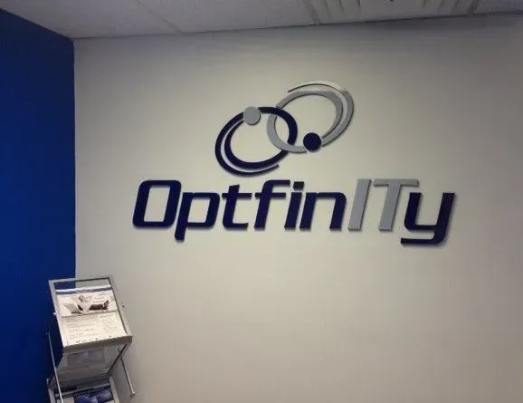 OptiNITY logo on a gray office wall with blue lettering and abstract linked-circle icon