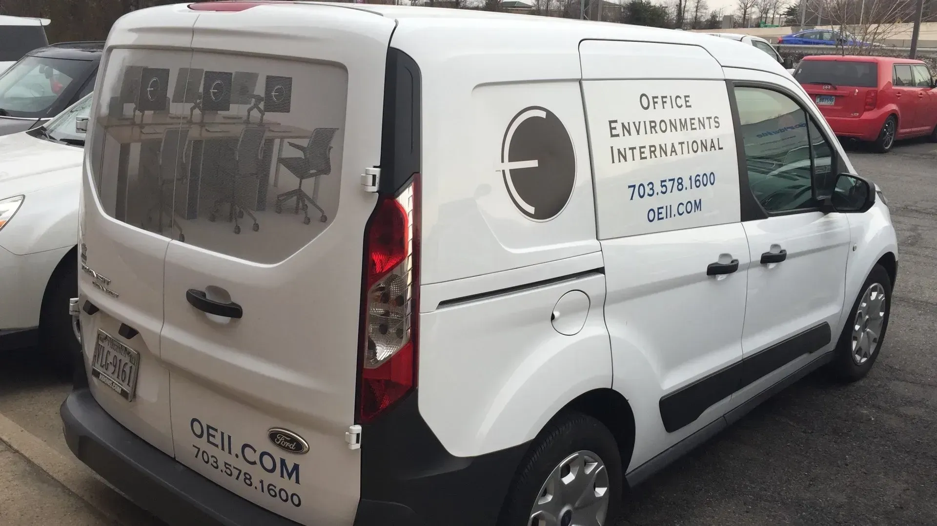 White delivery van parked outdoors with company lettering on the side and rear.
