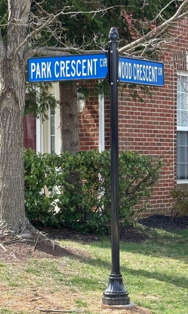 Blue street signs on a black pole at a brick corner, reading Park Crescent and Old Street.