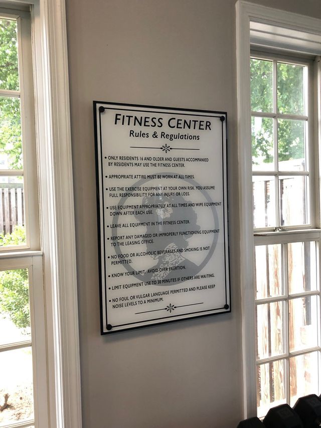 Fitness Center rules and regulations sign on a wall between two windows