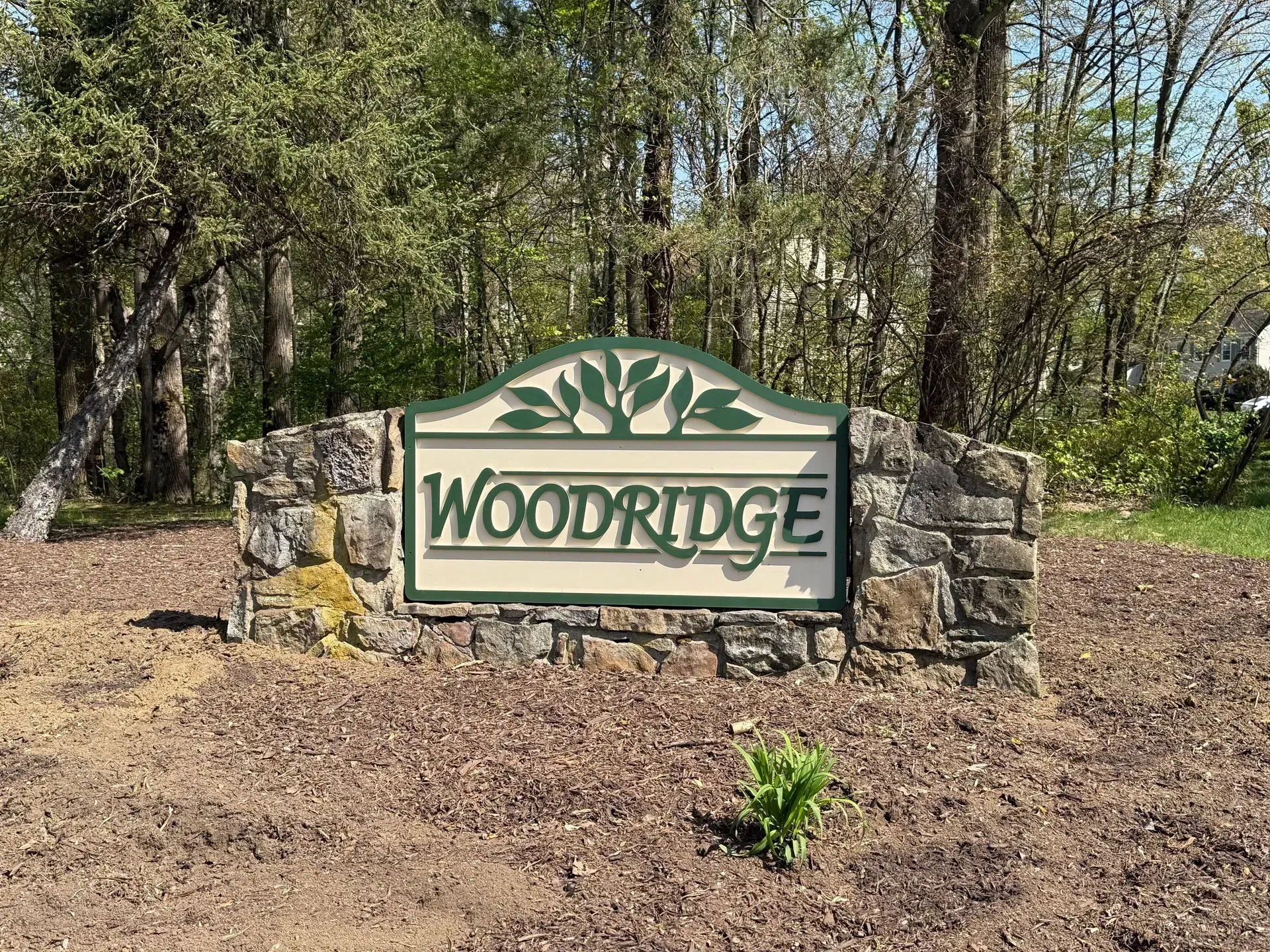Woodridge neighborhood entrance sign with stone pillars and trees behind it