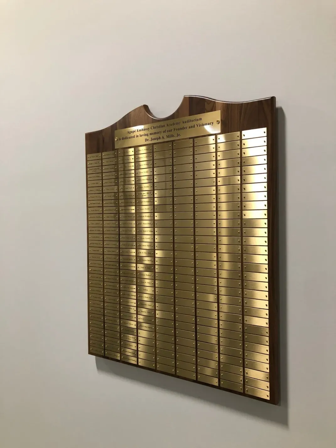 Gold memorial plaque with many engraved names mounted on a wall