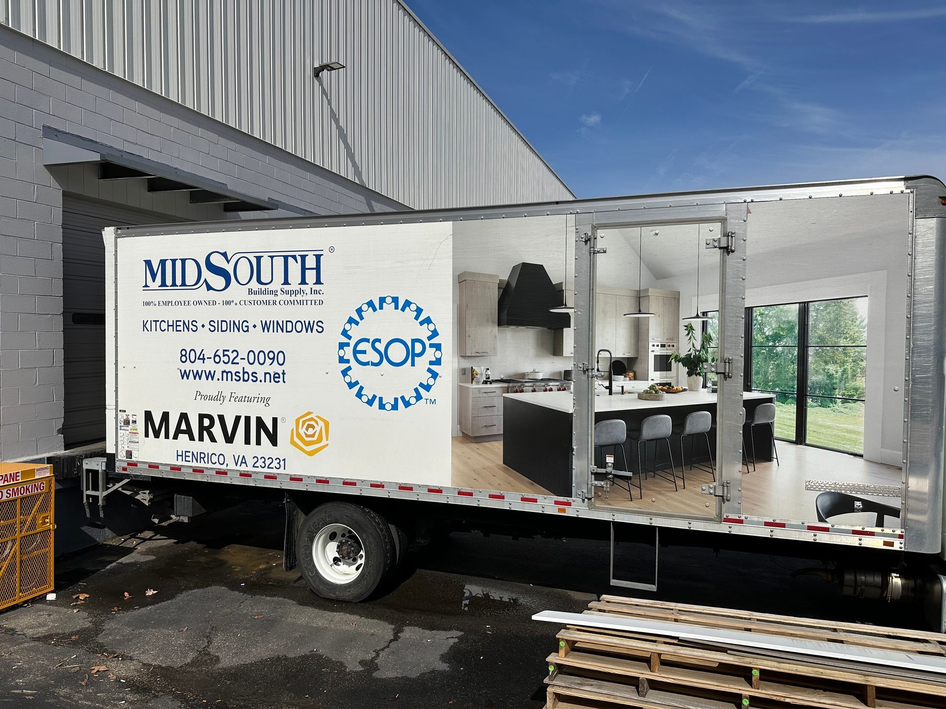 White MidSouth/Marvin service truck parked beside a building with its side open, showing workshop equipment inside