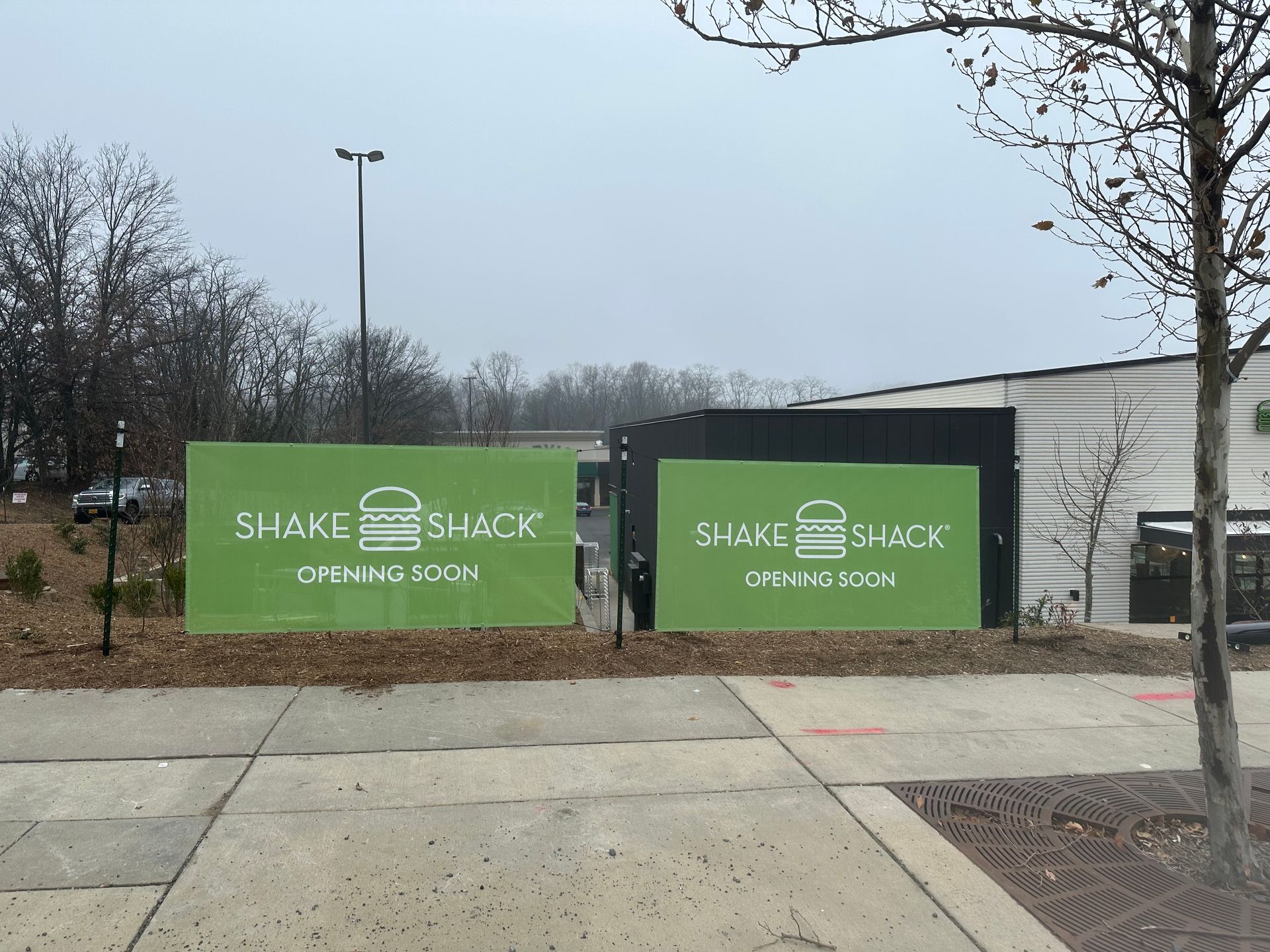 Green Shake Shack construction signs outside a building on a cloudy day