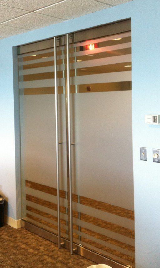Frosted glass double doors with horizontal brown stripes in a hallway