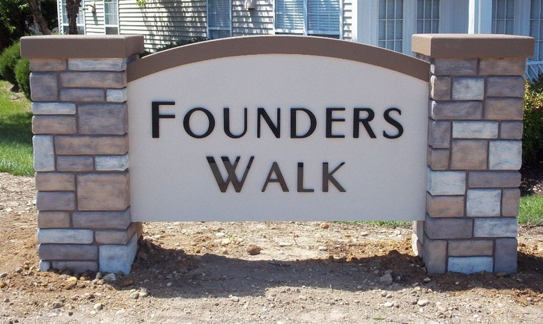Stone sign reading “Founders Walk” in a landscaped outdoor area