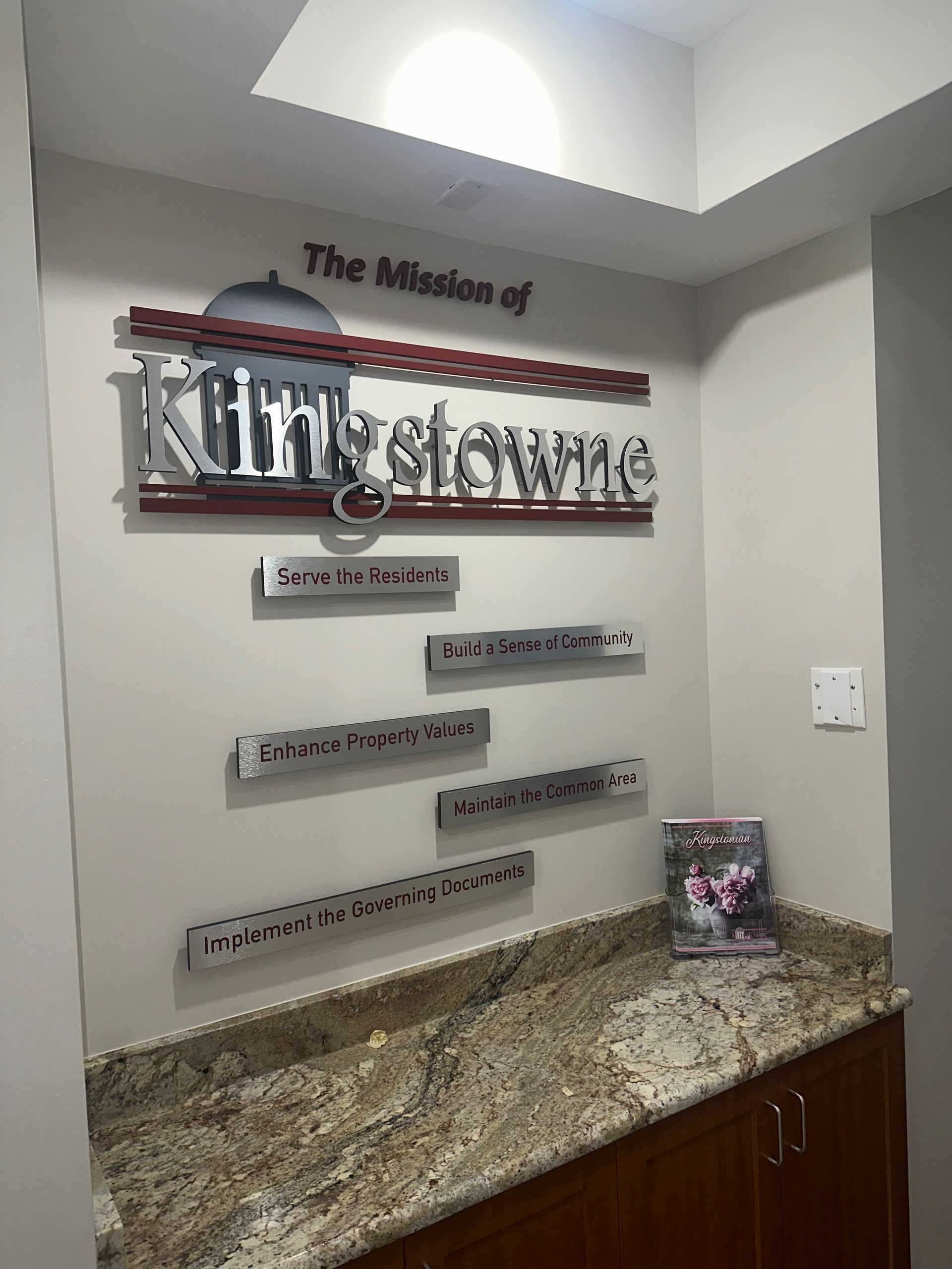Wall sign in a hallway with “The office of Kim Stawarz” above a granite counter