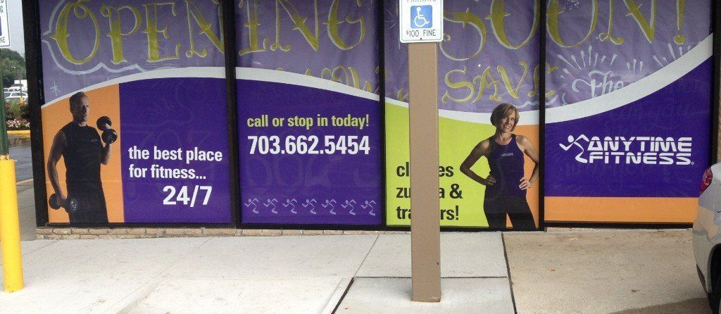 Storefront with purple “Open 24/7” and “Anytime” signs, plus a central pole in front