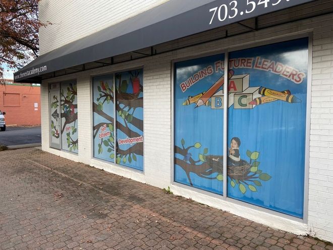 Storefront with blue-painted window murals and white brick exterior on a brick sidewalk