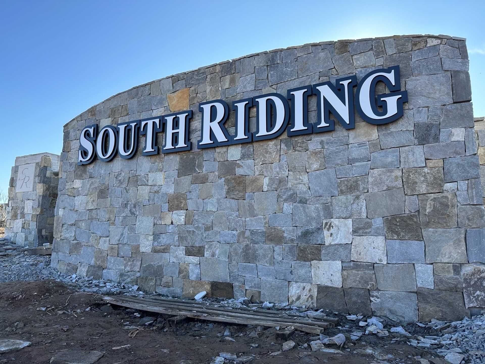 Stone wall sign reading “SOUTH RIDING” against a blue sky.