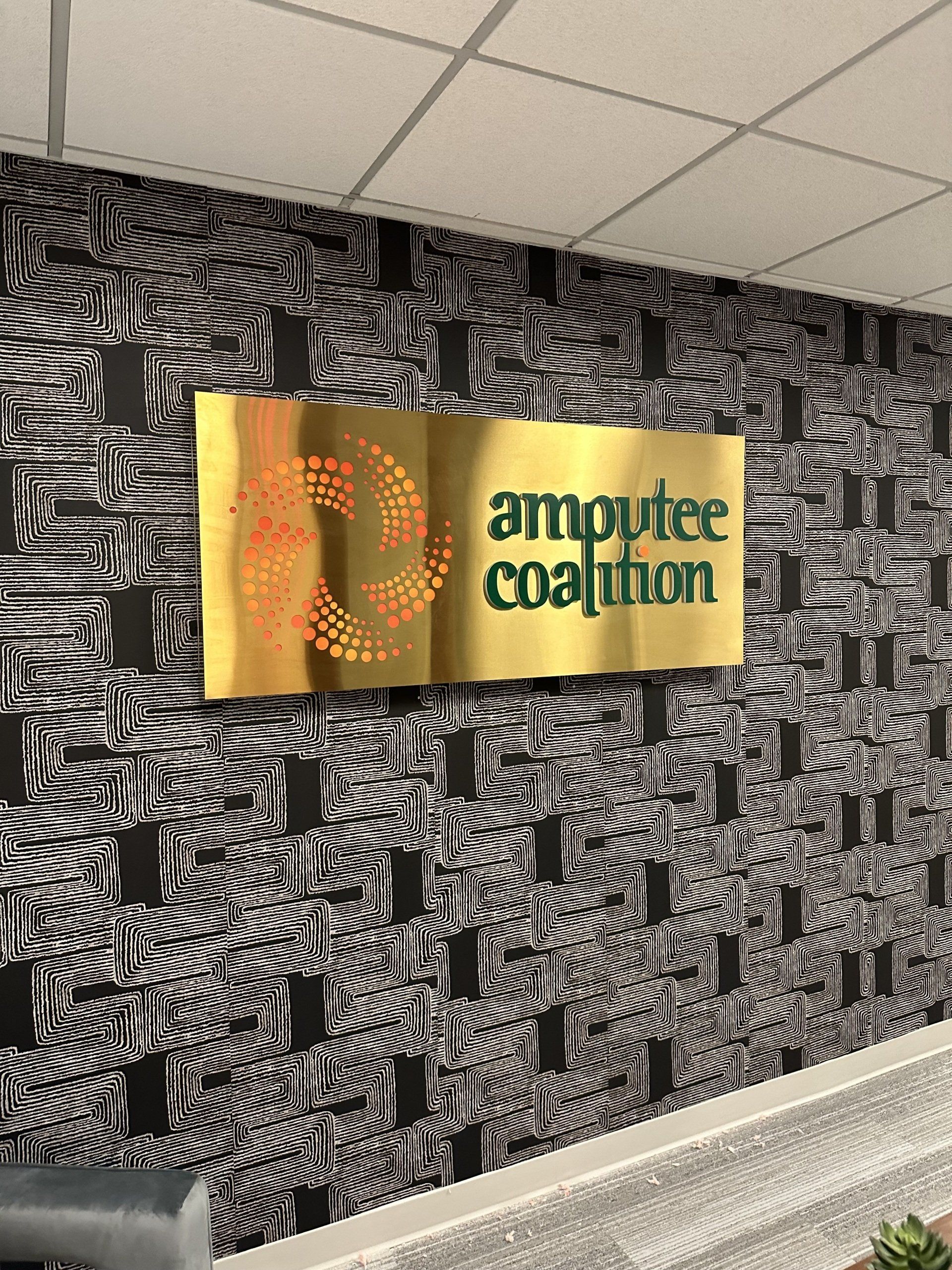 Yellow “amplifier coalition” sign on a black-and-white patterned wall in an indoor hallway