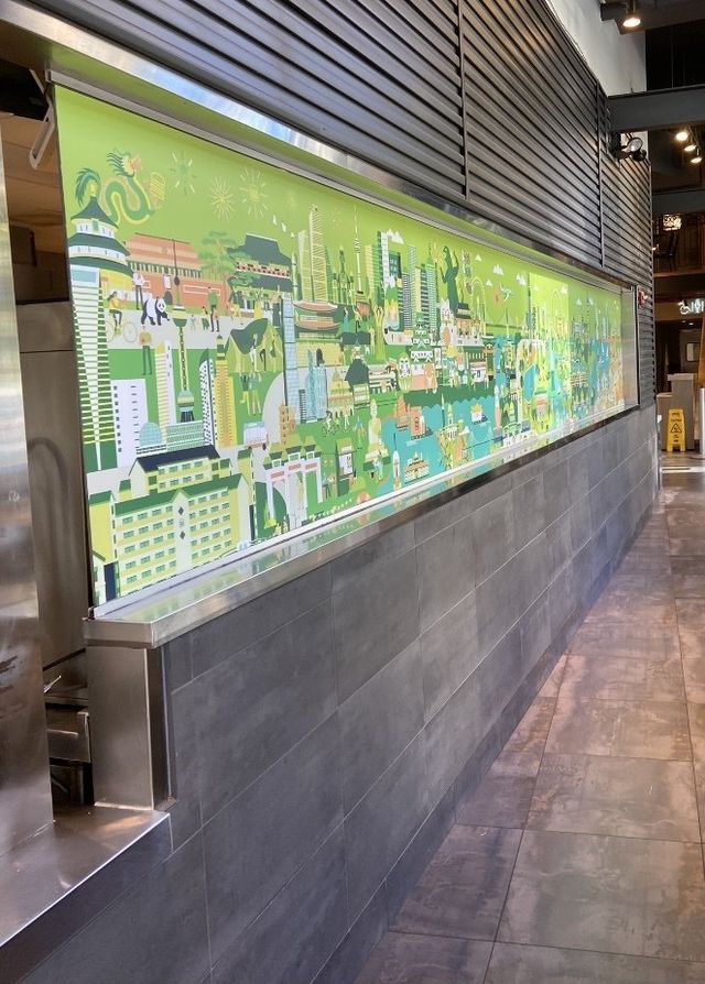 Colorful cityscape mural on a long wall in a modern indoor corridor with gray tile flooring