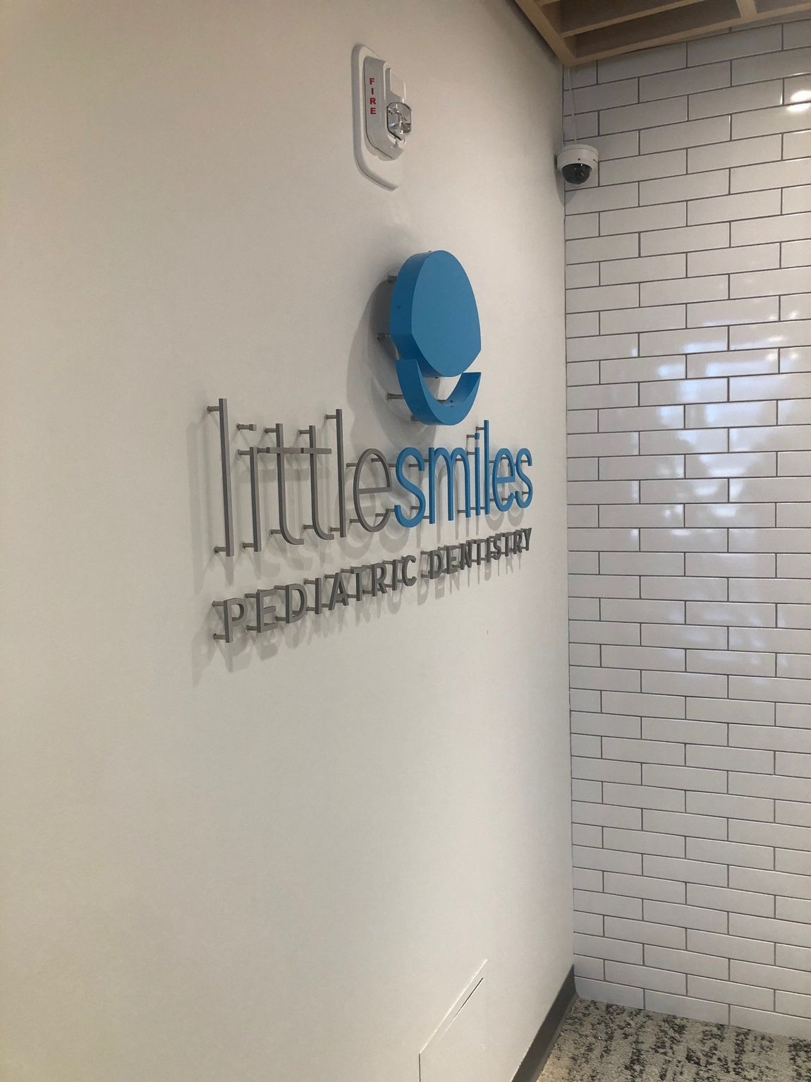 Little Smiles Pediatric Dentistry wall sign in a hallway with a blue circular logo