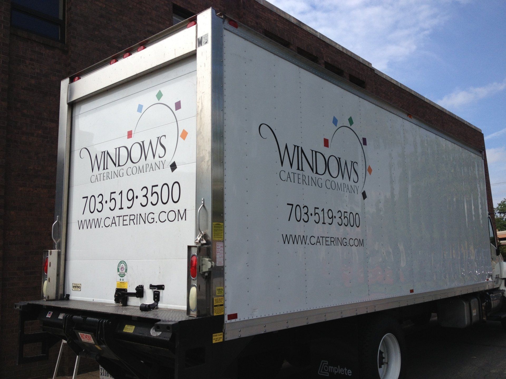 White Windows truck trailer with company logo and phone number parked outdoors