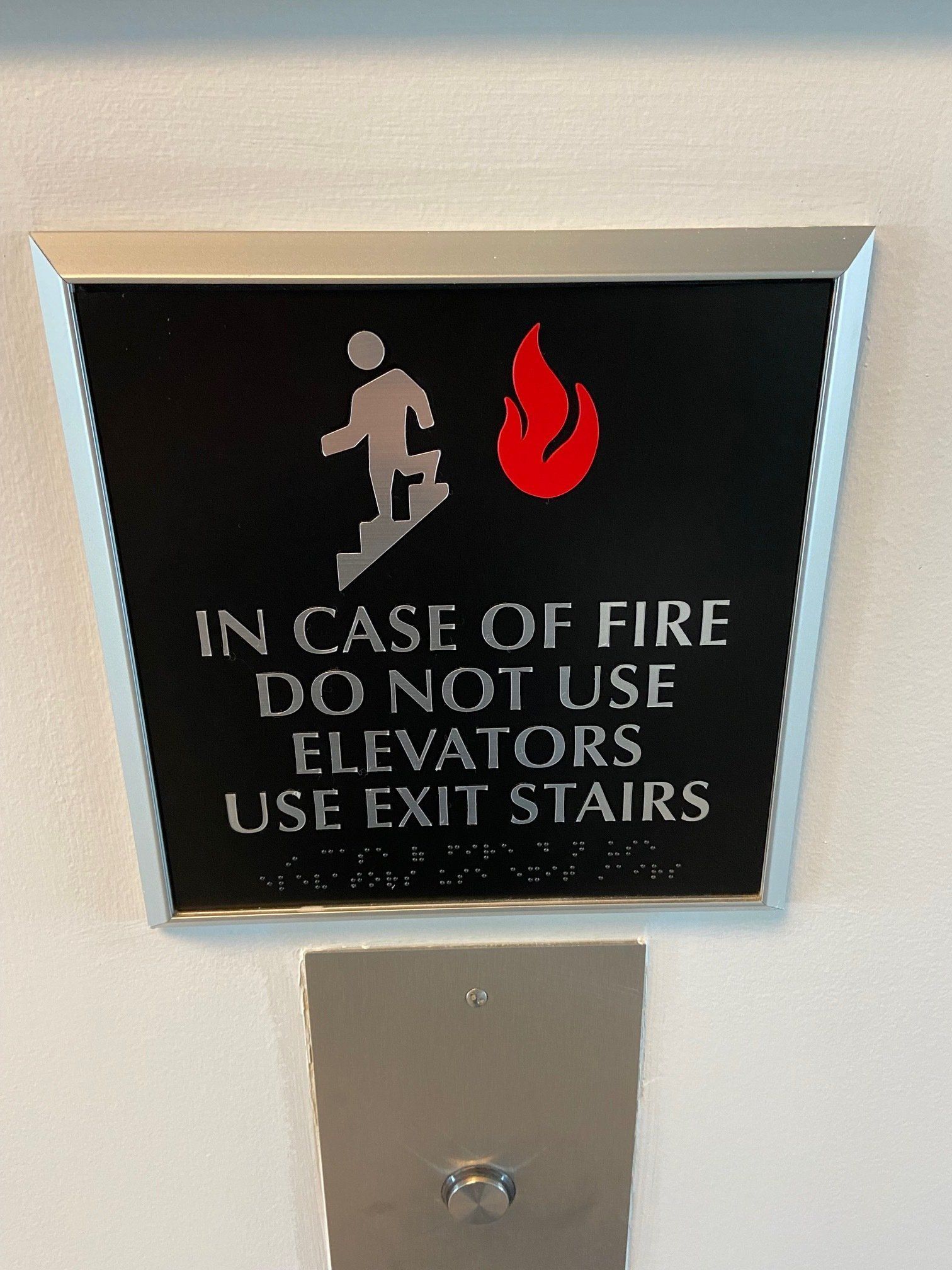 Fire safety sign in a metal frame: “In case of fire do not use elevators use exit stairs.”