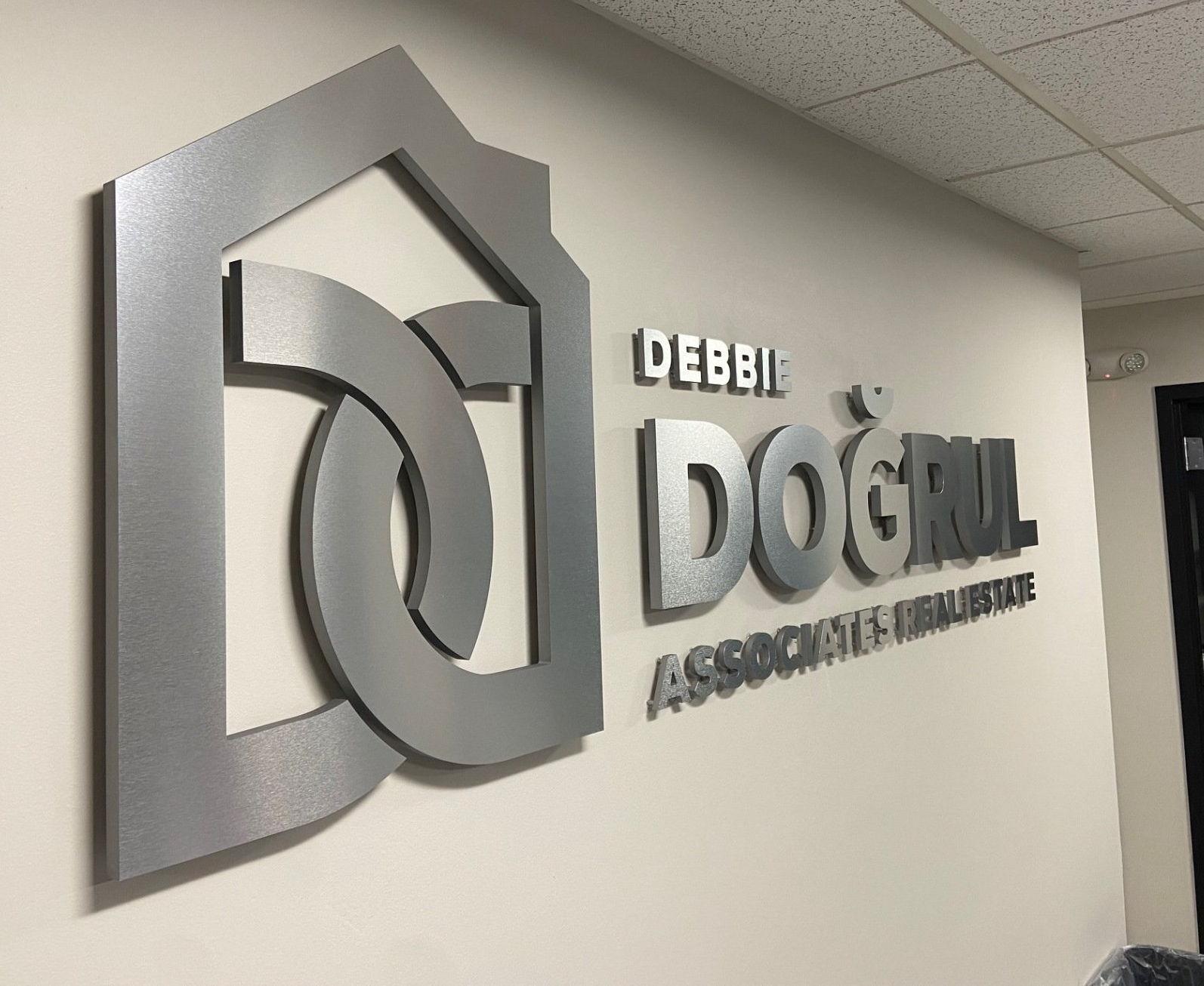 Wall sign for Debbie Doggill Association, silver 3D lettering on a beige office wall