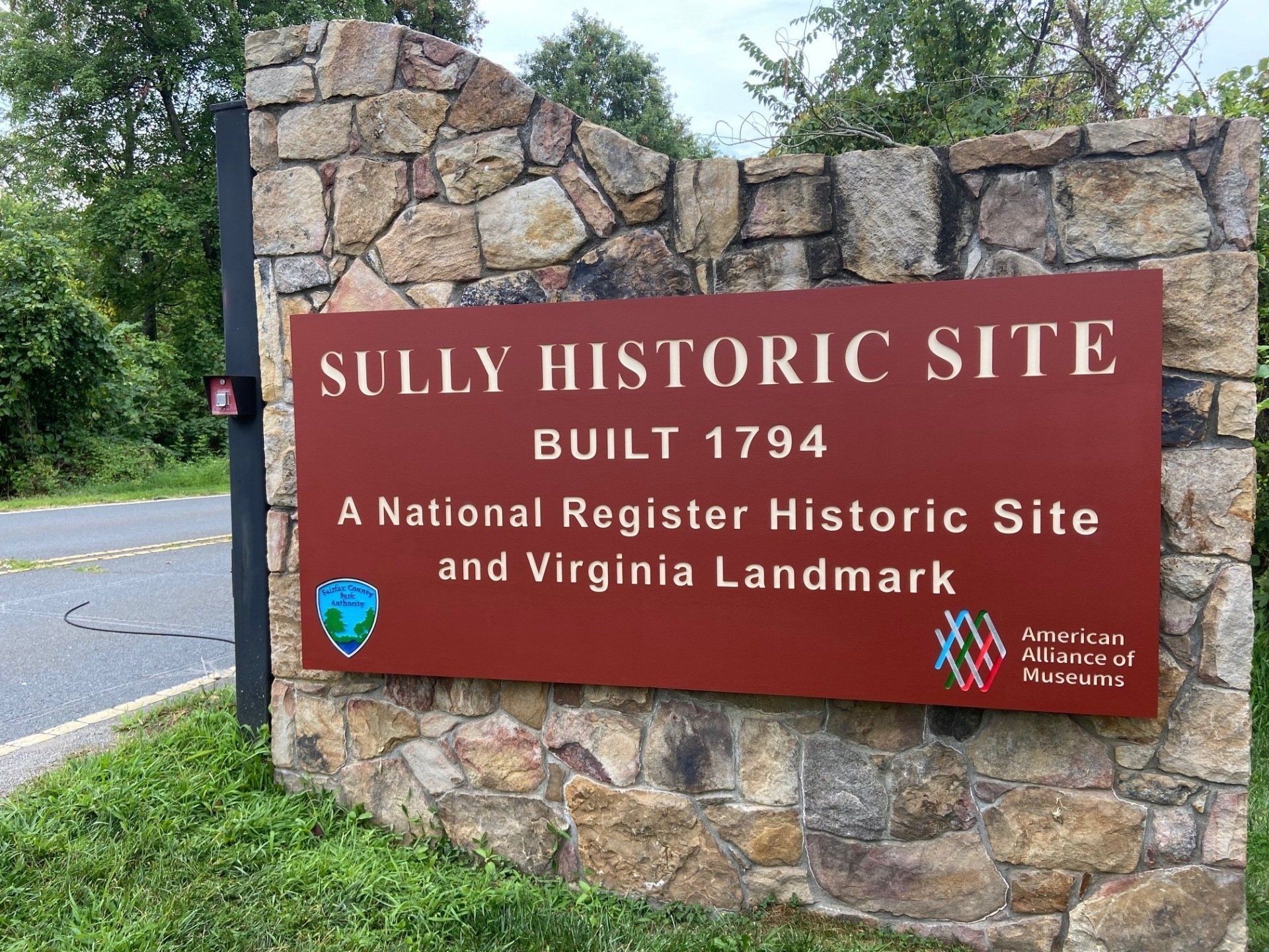 Sully Historic Site sign on a stone wall, red plaque reading Built 1794 in Virginia.