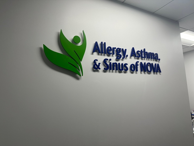 Wall sign for Allergy, Asthma, & Sinus of Nova with green logo on a gray wall