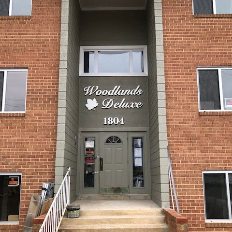 Entrance to Woodlands Deluxe apartment building, brick facade with gray doorway and number 1804