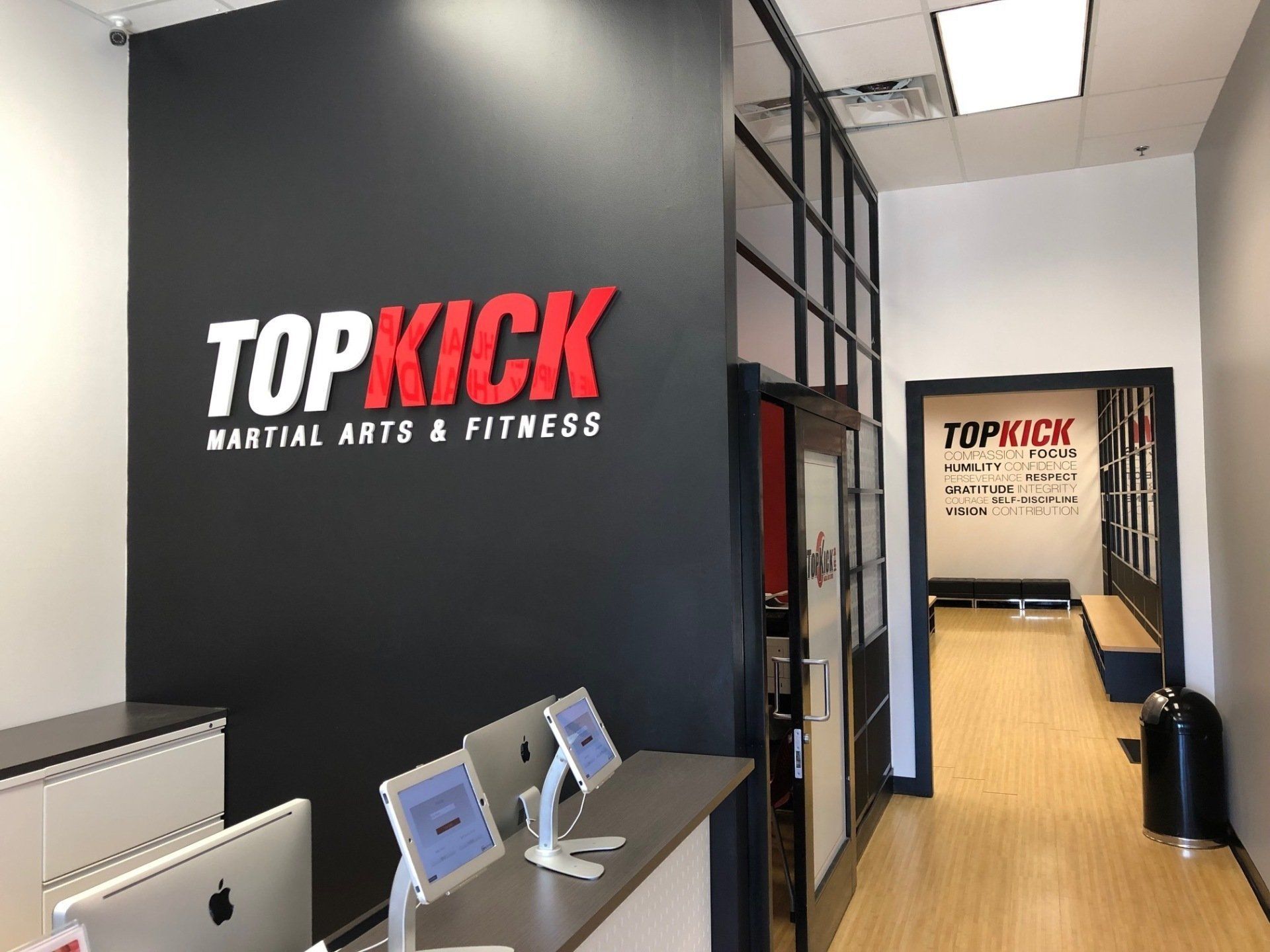 Hallway entrance to Top Kick Martial Arts & Fitness with black wall sign and reception desk