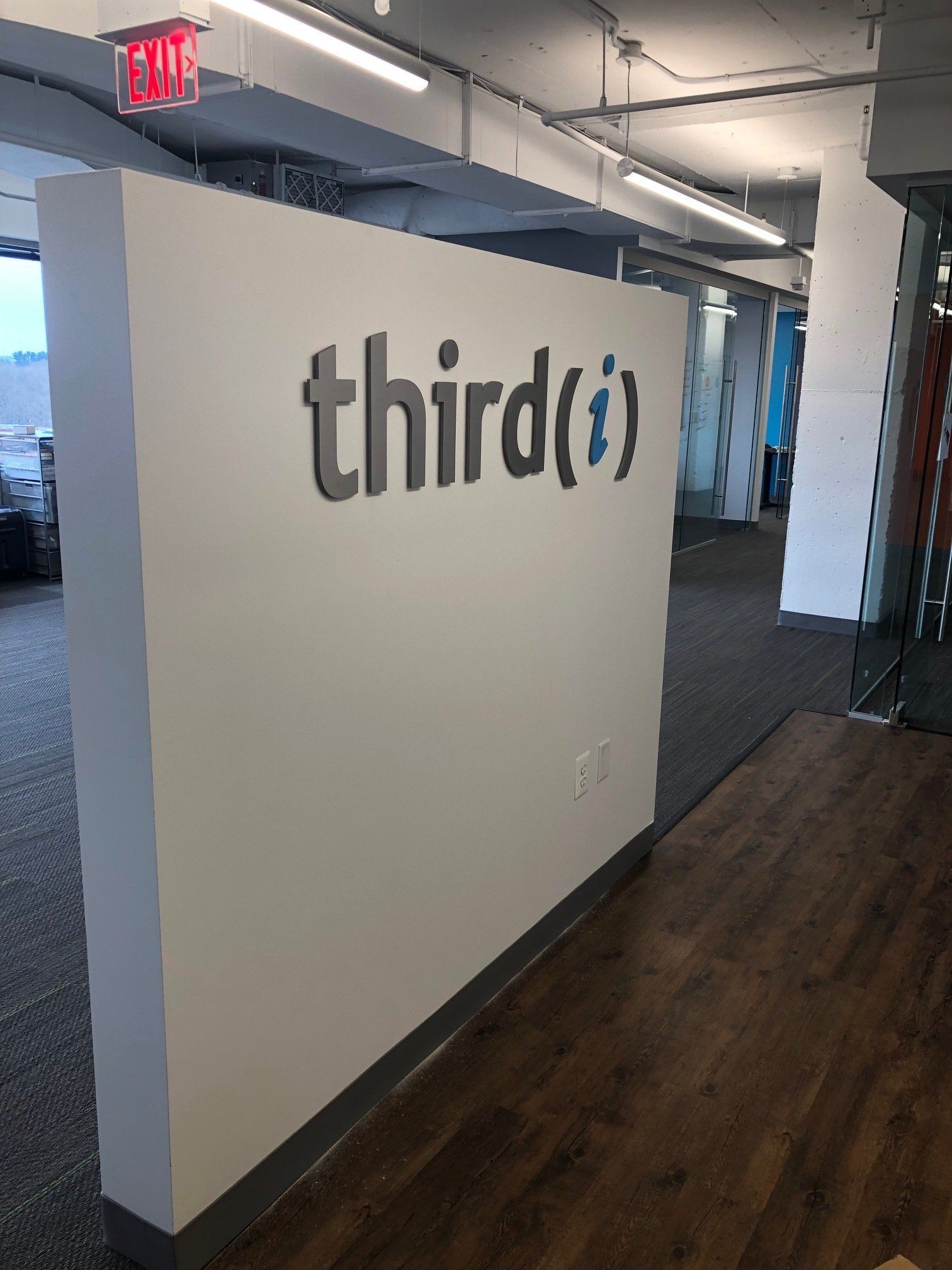 Office hallway with a large white wall displaying the “thirdi” logo.