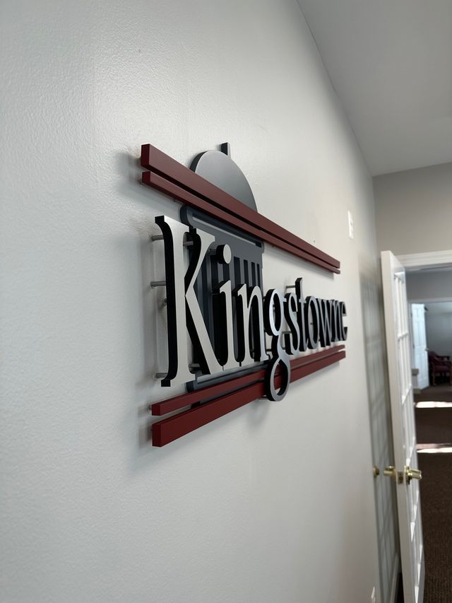 Kingstone wall sign with black and maroon lettering in a hallway
